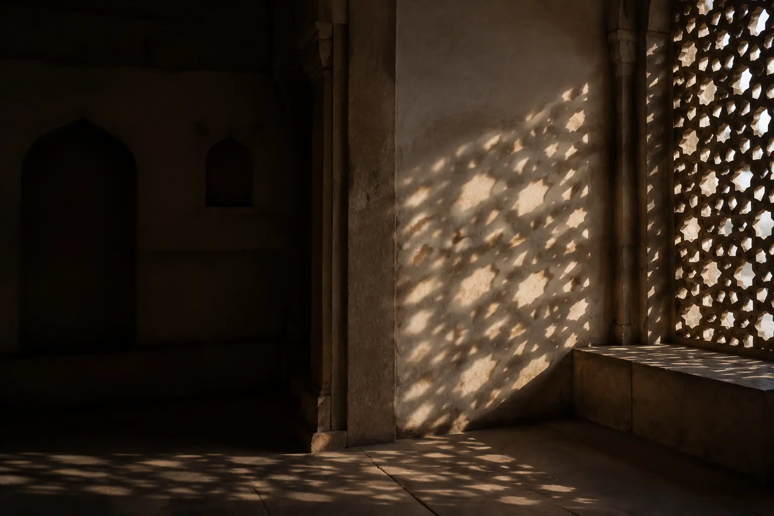 Hard afternoon sunlight falling through a carved stone jali screen
