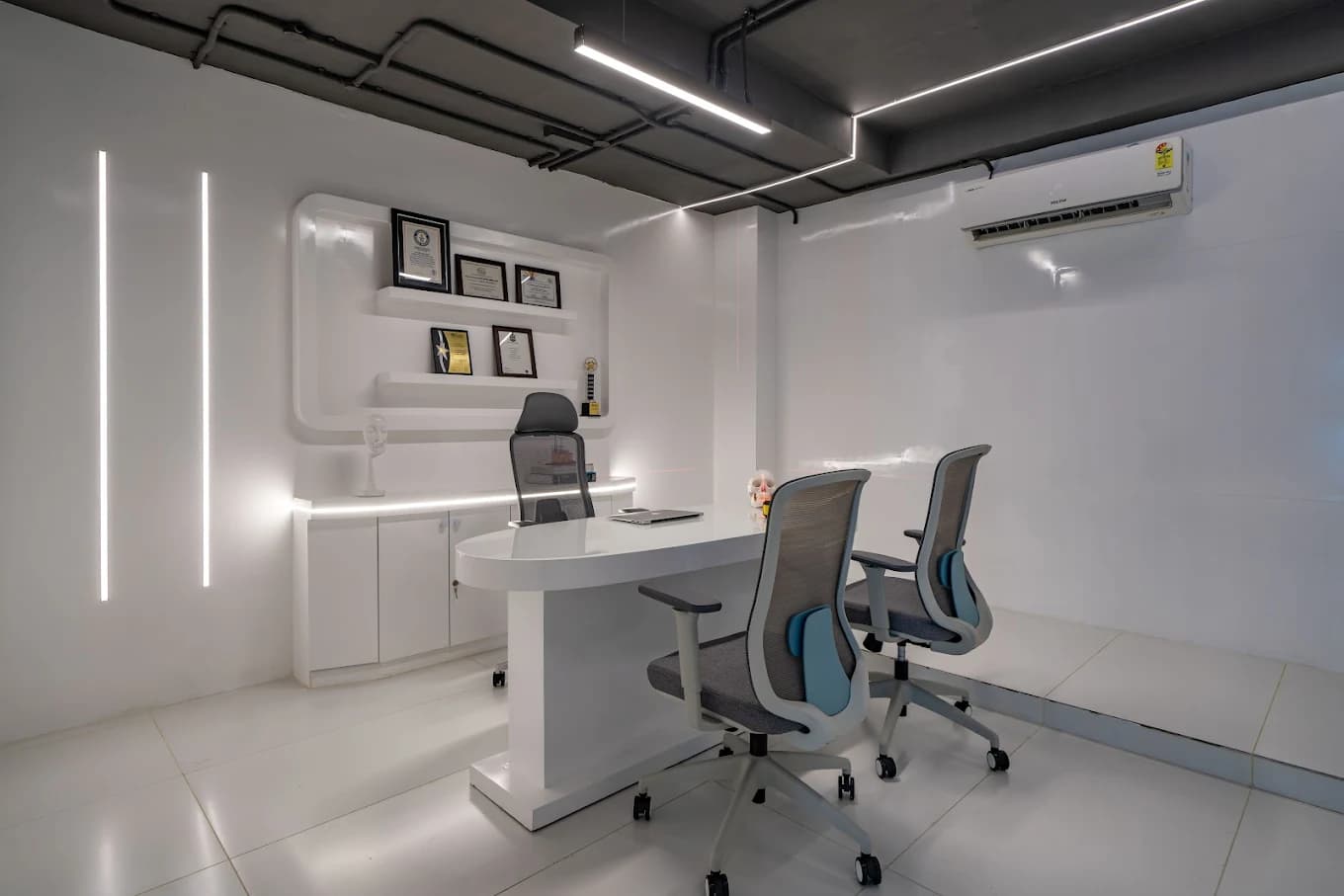 A Genoryx consultation room with a white desk, two visitor chairs and framed certificates on the wall
